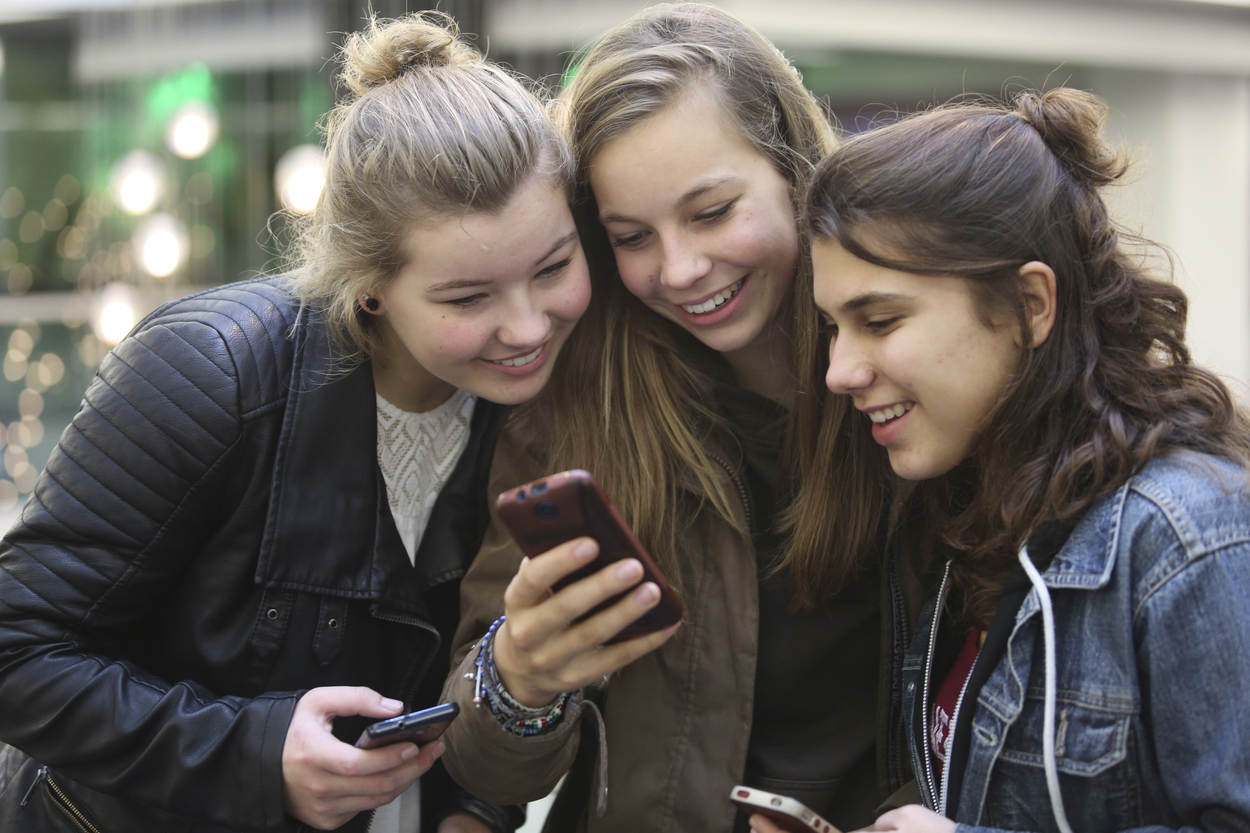 Drie tieners met smartphone buiten