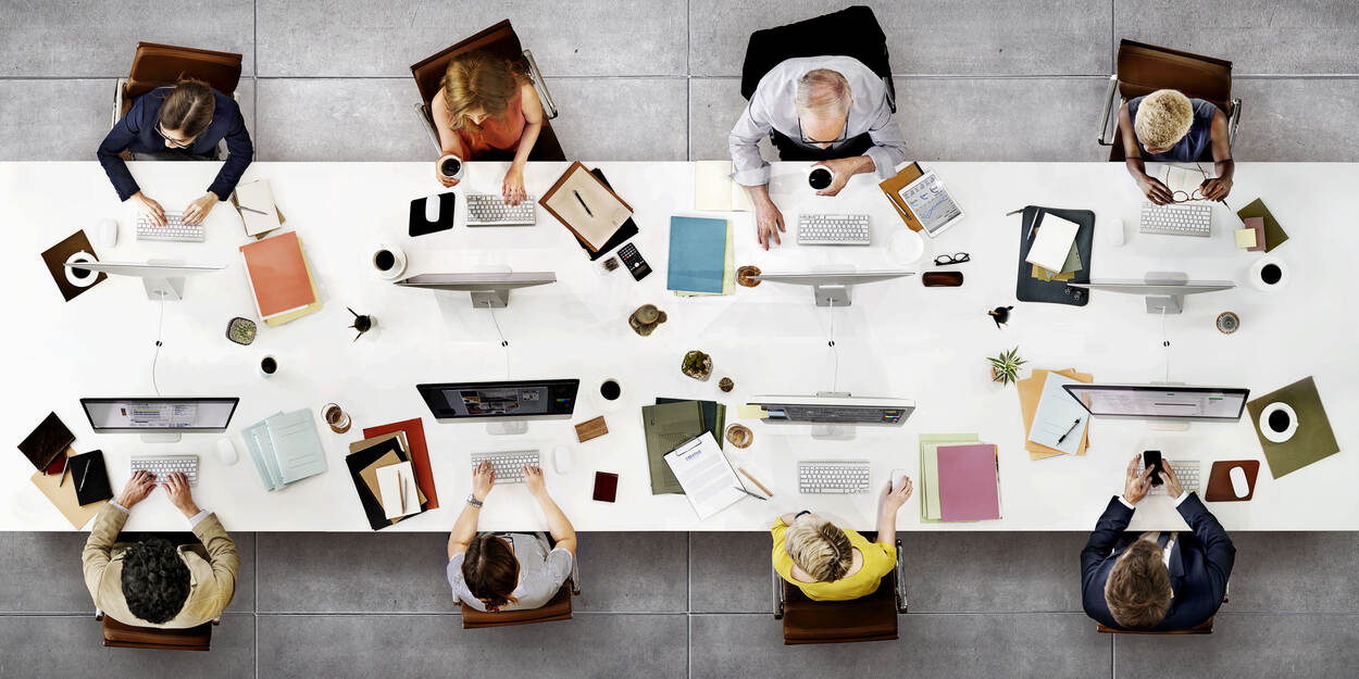 Mensen aan een tafel met laptops en andere apparaten