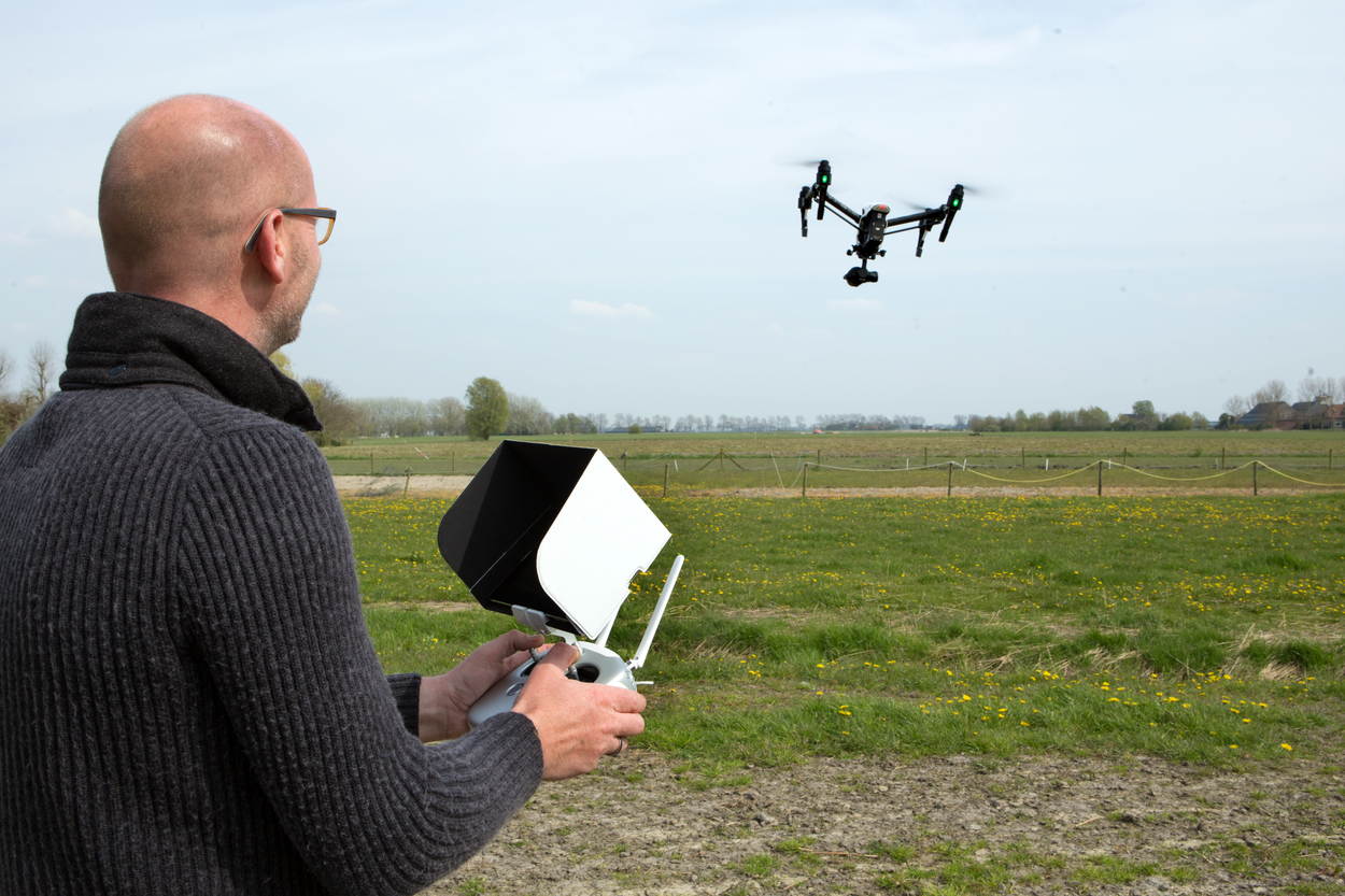 Man die drone bestuurt in een grasveld