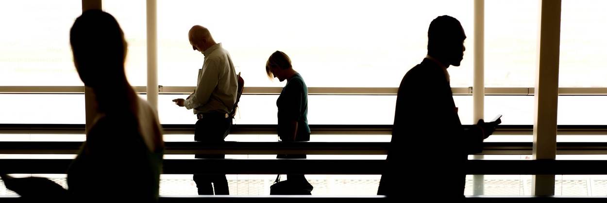 Mensen kijkend op hun telefoon op de loopband van een vliegveld