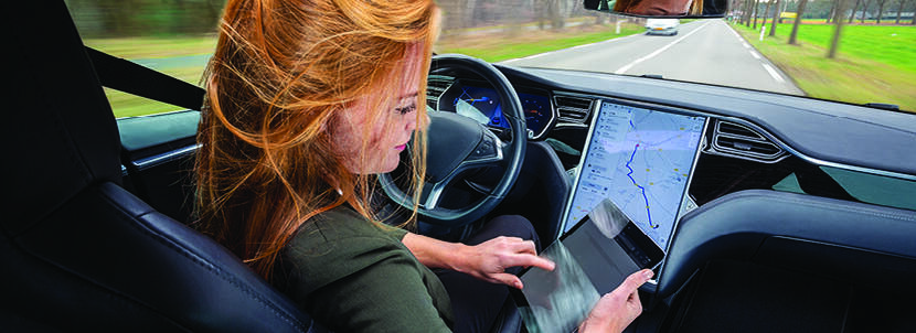 Vrouw in zelfrijdende auto met ipad voor zich