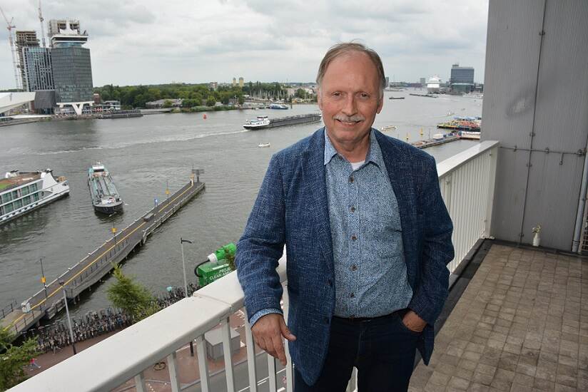 Jaap Nab staat op een balkon, met op de achtergrond de haven van Amsterdam
